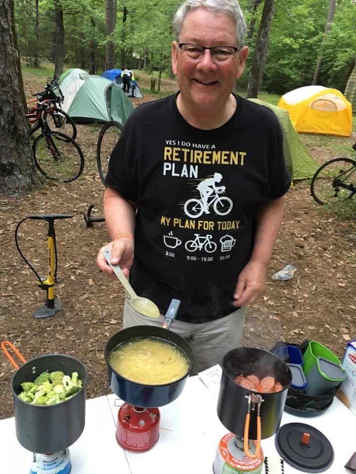 Alumni Coordinator, Neil McCallum cooking food in camp.