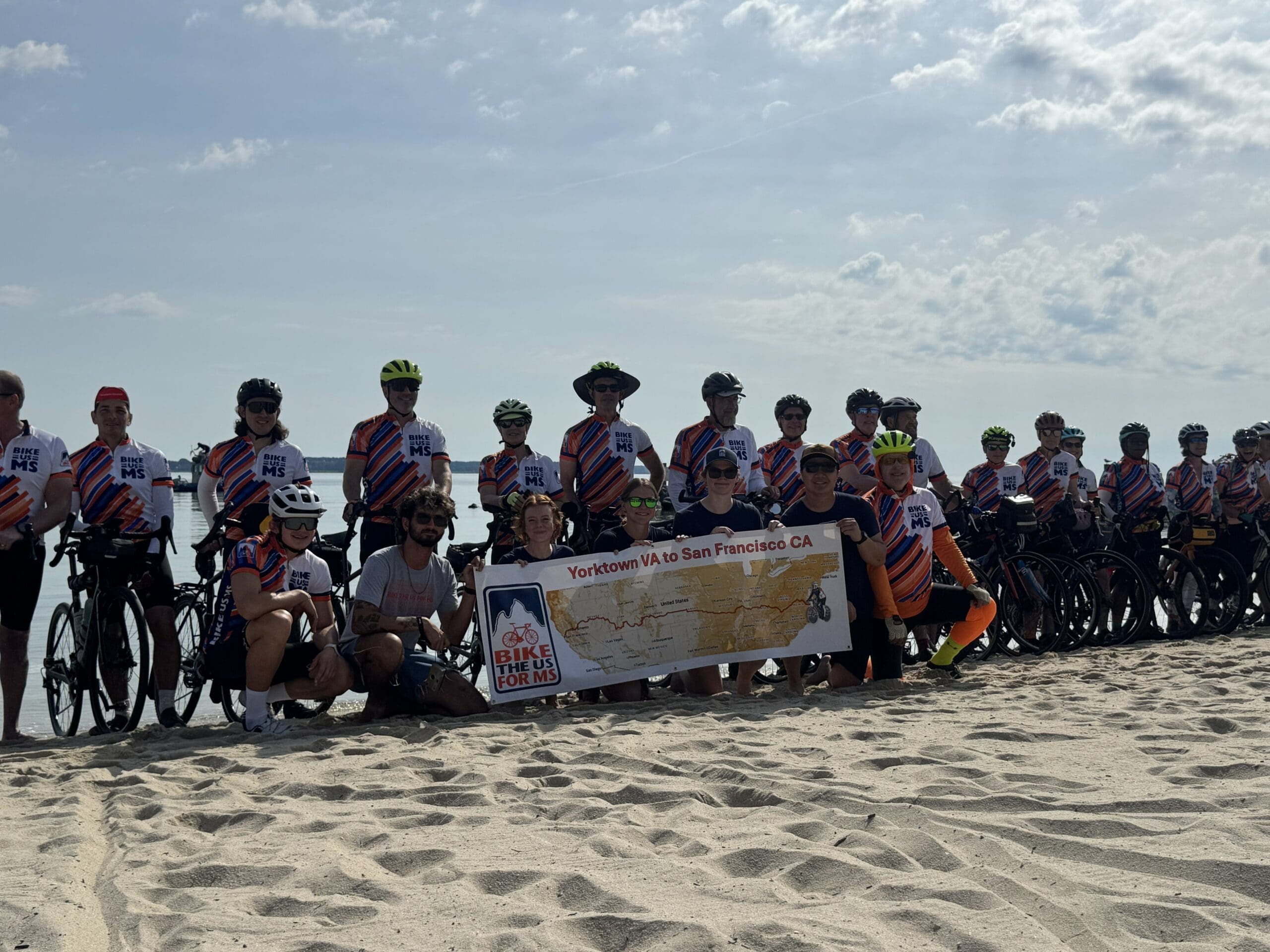 a team of 30 Bike the US for MS cyclists posing for a photo with a banner that shoes their journey from Yorktown to Virginia