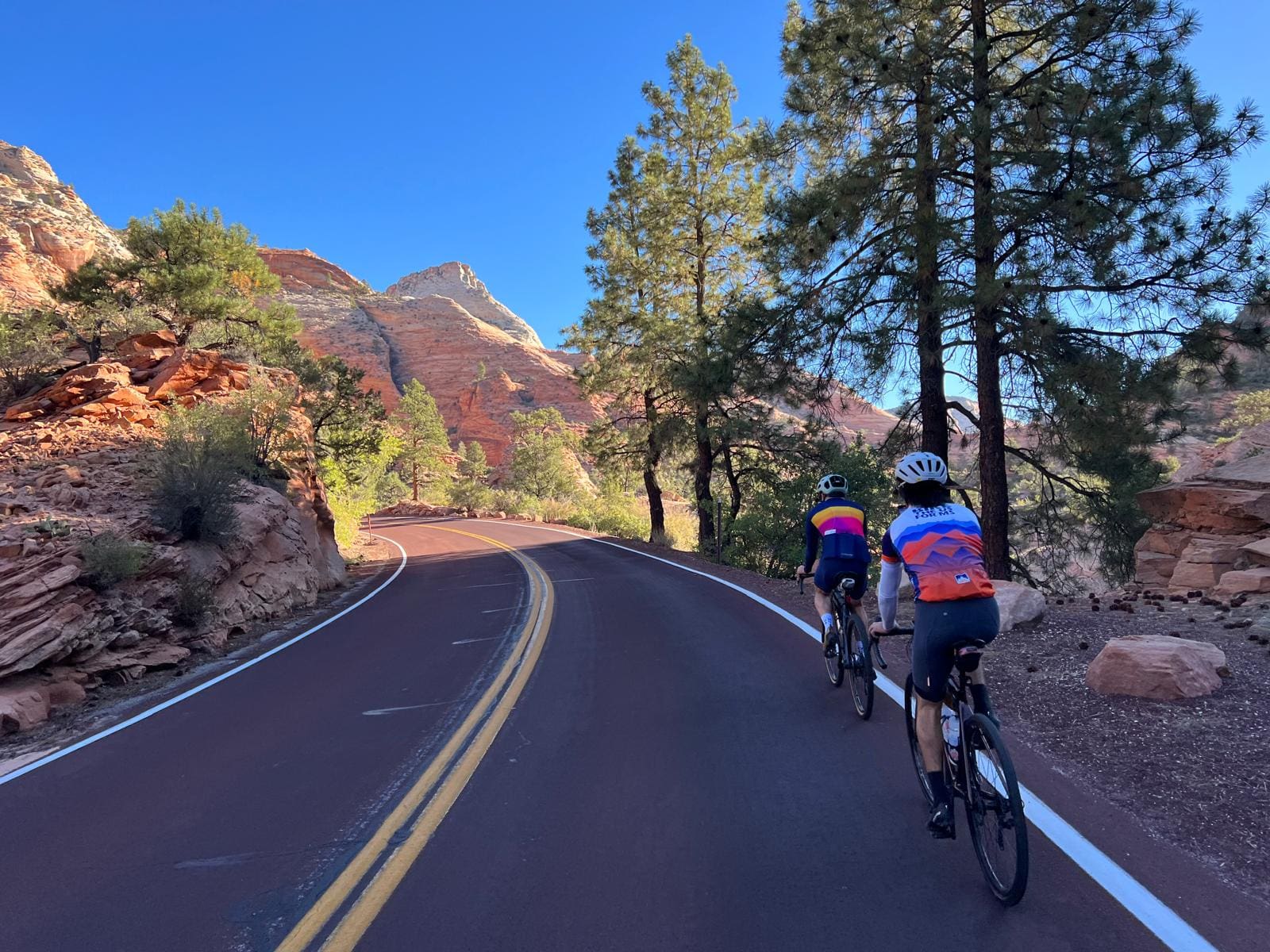 Two Bike the US cyclists riding along a paved road through red rocks and Canyons in Arizona.